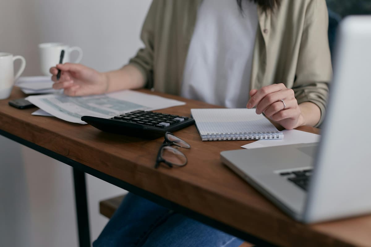 iva - Impuestos al comprar una nueva vivienda | Mujer trabajando y revisando papeles y facturas