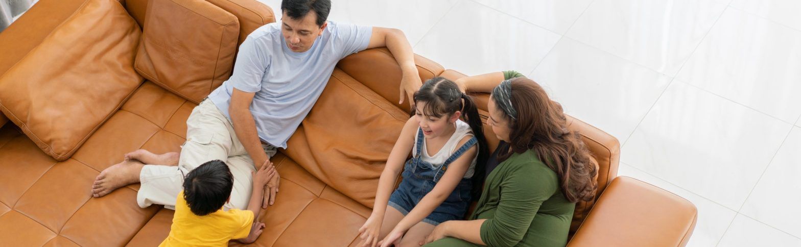 Familia feliz en el sofá de una vivienda de obra nueva para familias.